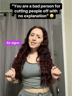 A woman stands in a bathroom, wearing a gray tank top and gray sweatpants. She has long, dark, wavy auburn hair. Over her head, a black rectangle contains white text. Below it, a purple rectangle reads, 'Air signs:'.