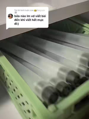 The image shows a close-up view of a green plastic container filled with clear plastic containers that hold something black. The containers are angled, and the background is blurred, also green, indicating the setup is probably indoors.