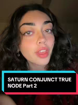 A young woman with long, wavy dark hair is centered in the frame, looking directly at the camera with a gentle smile. The background is dimly lit. In the lower third of the frame, a black rectangle with a red and blue gradient bottom banner provides a text overlay: "SATURN CONJUNCT TRUE NODE Part 2".