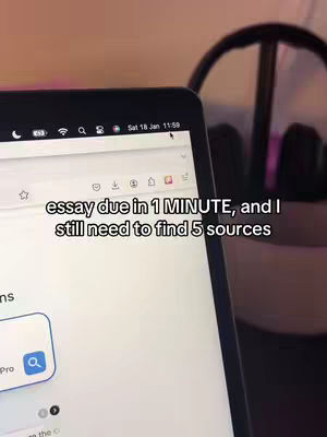 A laptop screen is the focal point, displaying a website with the browser's address bar visible. Text overlay reveals a time-sensitive situation: "essay due in 1 MINUTE, and I still need to find 5 sources." The background includes out-of-focus elements like headphones and what appears to be a desk near a window. The composition is straightforward, emphasizing the urgency of the task.