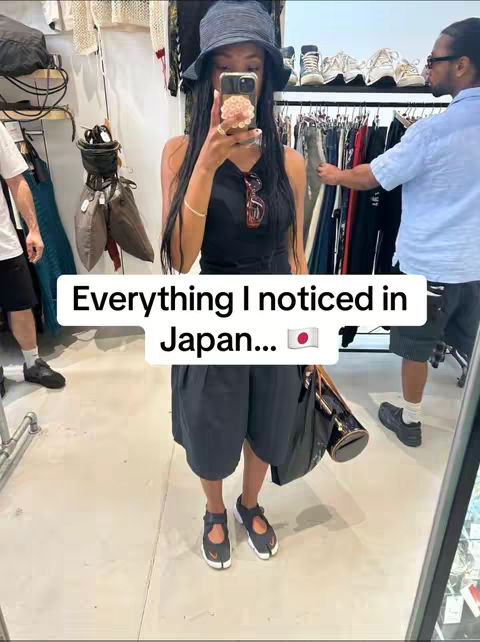 A woman takes a mirror selfie holding her phone with her right hand. She is in a shop with clothing racks and other items in the background. The hook text hovers over the selfie.