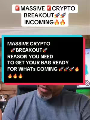 The cover image features a man speaking with two layers of overlaid text, one at the top and another in a black box. The top layer has the words "MASSIVE CRYPTO BREAKOUT INCOMING" with several emoji like a rocket, and a fire icon. The second text overlay in the style of a title card says "MASSIVE CRYPTO BREAKOUT REASON YOU NEED TO GET YOUR BAG READY FOR WHATS COMING ." The man has a gray or salt-and-pepper trimmed beard and is casually dressed in a gray t-shirt. The overall lighting is moderate, and the background is blurred or out of focus, keeping the viewer's attention on him and the text.