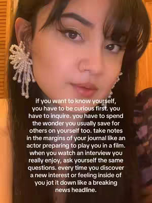 A close-up shot of a woman with long dark hair, wearing large, ornate earrings. The background appears to be a warm, reddish-brown tones, likely wood. The woman is looking slightly to the side with a neutral expression. Text is overlaid on the image in white font.