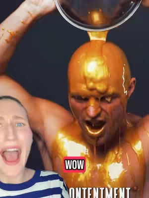 The image shows a person being covered in a golden liquid, possibly honey or paint, with another person in the foreground expressing shock and joy. The background is a dark, solid color. Text overlays reading 'WOW' and 'ONTENTMENT'.