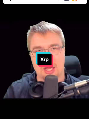 A man with glasses is positioned in front of a black background, holding a microphone. Over his face is a colorful box with the text 'Xrp' in white. The lighting is soft and focused on the man, and the overall composition is centered.