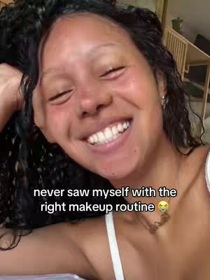 The cover image is a selfie of a woman with curly black hair, smiling broadly with closed eyes. The text overlay says, "never saw myself with the right makeup routine." She wears a white top and delicate gold necklace. The background subtly shows a wooden structure.