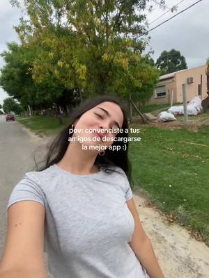 A young woman is smiling as she walks along a tree-lined street, slightly angled with text overlayed. She wears a gray t-shirt.