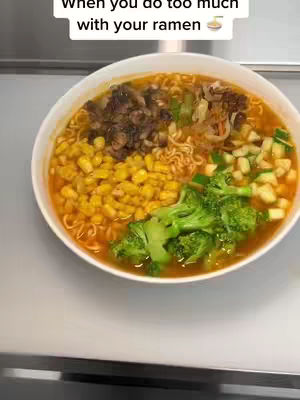A top-down shot of a white bowl filled with ramen. The ramen broth is visible, and there are sections of different toppings: corn, broccoli, mushrooms.