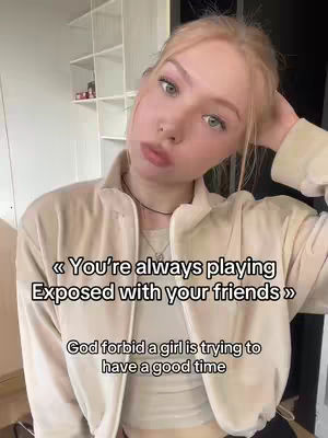A young woman with blonde hair is the central focus. She wears a light-colored, open jacket over a white top. The background is a softly lit interior with a white storage unit and a glimpse of another room. Text overlays are added to the image.