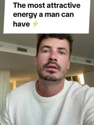 A medium shot features a man in a white sweater against a neutral background of an indoor setting. Above him, a text overlay reads: 'The most attractive energy a man can have' in a white box with a lightning bolt symbol.
