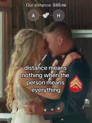 A cover image showing a couple embracing. The couple is positioned closely together, with the woman in the foreground wearing a white dress with lace and a floral hairpiece. The man in the background is in a military uniform, wearing his arms around her. Text overlaying the image includes the distance between two places.