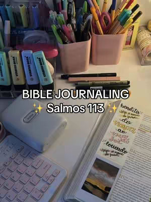 A desk setup with bible journaling supplies. Various colorful pens, highlighters, and other stationery items are arranged on the desk, including a small white object and a keyboard. The image is mostly focused on the objects, and the colors such as pink, blue, and yellow make the image attractive and appealing.