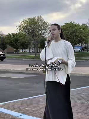 A woman stands outdoors, holding a microphone and a book, likely preaching. The background includes trees, a street, and a cloudy sky. Text overlayed on the image reads, 'receive Jesus today because even in this life.'