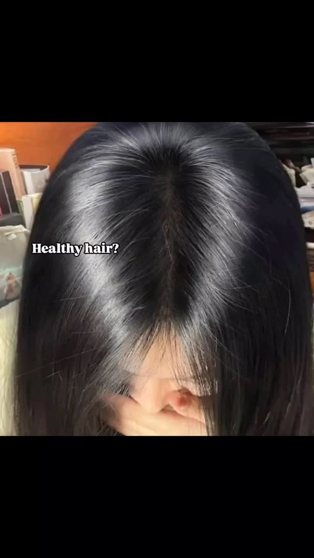 A close-up shot showcasing the top of a person's head, with long, black, healthy-looking hair. The hair is parted slightly off-center, and the image is well-lit, reflecting the light and creating a glossy appearance. Text overlayed on the image poses a question.