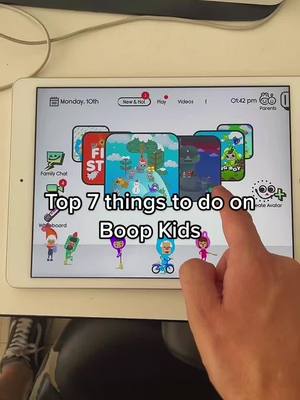 The image shows an iPad screen displaying a game interface, with text overlayed on the screen that reads "Top 7 things to do on Boop Kids". A hand is touching a spot on the screen. The background includes a white table and partially visible sneakers.
