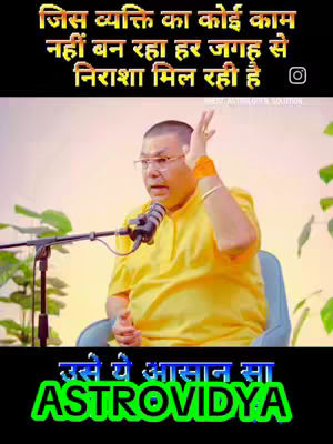 The cover image for this video features a middle-aged man wearing glasses and speaking into a microphone. He's dressed in a yellow shirt and sitting in a blue chair. Behind him, there's a light-colored background, possibly indicating a studio setting. Text overlays are present in both Hindi and English on the image. The text is designed to capture attention and convey the video's subject, which appears to relate to astrology.