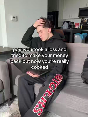A young man is sitting on a sofa, looking distraught with his hand on his forehead. Text overlay describes a financial loss. He is wearing a black hoodie and sweatpants with the word "RUTGERS" down the side, suggesting he may be affiliated with the university.