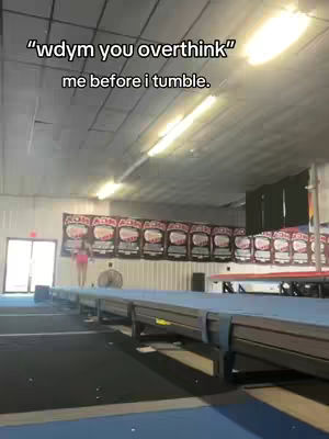A young woman in a pink top is standing on a blue tumbling mat in a gym. Above her is text overlay saying "wdyw you overthink" and "me before i tumble."