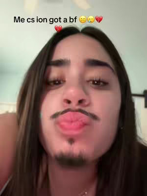 A close-up shot of a person's face, with an added mustache and goatee, creating a humorous effect. The face is framed with long hair, and text overlays above the head, using the image to create a funny contrast.