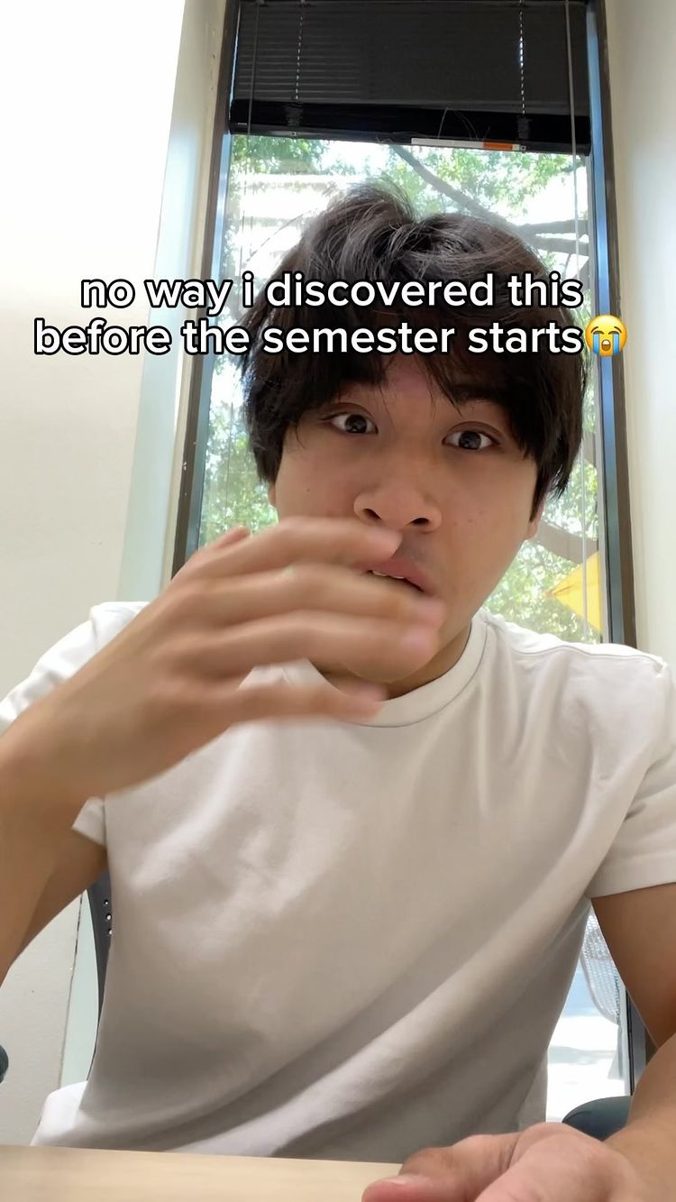 A young man with dark hair and a white t-shirt is looking surprised and holding his hand up to his face. Text overlayed on the image reads, "no way i discovered this before the semester starts" and also includes a crying face emoji.