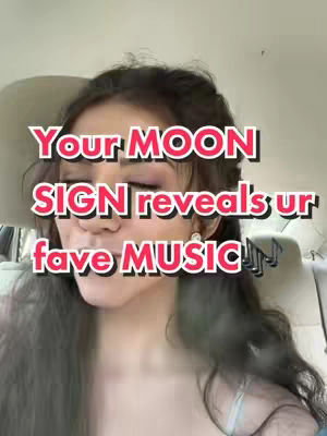 A selfie-style shot featuring a woman in a car. The upper body is visible, with the focus on her face where a text overlay reads 'Your MOON SIGN reveals ur fave MUSIC!'. She has long hair and is wearing minimal makeup. The background shows the car's interior with headrests.