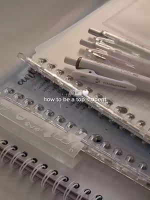 The cover image shows a close-up of school supplies including white pens, clear ring binders, and a spiral notebook. The text overlay reads 'how to be a top student'.The color palette consists of neutral tones, creating a clean and organized feel. The layout focuses on the stationary with soft lighting.
