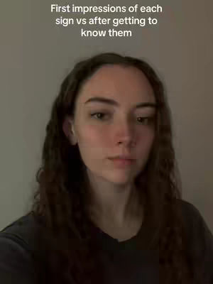 A person with long, wavy brown hair and a dark shirt is centered in the frame, looking directly at the camera. The background is a plain, muted shade, and text overlays the top portion of the image. The overall composition is simple, focusing on the individual.