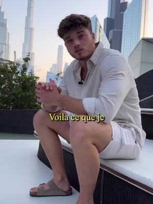 A man is sitting on a white surface with a city skyline in the background. He is wearing a light-colored button-down shirt and white shorts. The text overlay is yellow.