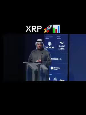 A man in traditional Arabic attire stands behind a clear podium at a conference. Behind him is a dark blue backdrop with logos and text. Above the man, the word "XRP" is displayed with a rocket ship and bar graph emojis. The overall color scheme is dark, with the man's outfit providing a lighter balance.