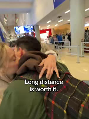 The cover image shows two people embracing and kissing in an airport. One person is facing the camera while the other is turned away from it slightly but is in the process of kissing the other. Behind them, a bustling airport environment is visible with people and signs.