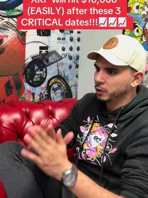A man in a white baseball cap and a black hoodie sits on a red sofa, talking to the camera. A text overlay in a red box appears at the top of the image, and a graphic is visible in the background.