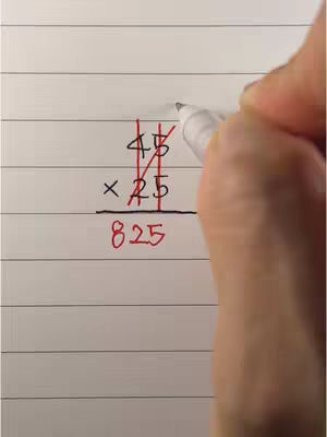 A hand holding a pen is writing on a sheet of lined paper. The paper features a multiplication problem written out, with the numbers 45 and 25 positioned above and the answer 825 below, showing the process of calculating the answer with lines through each number.