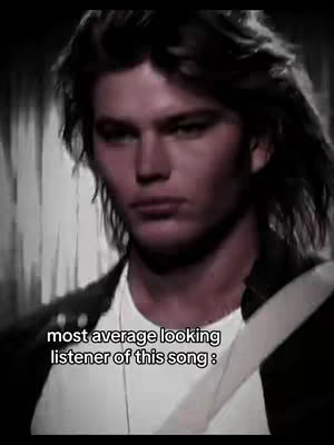 A grayscale image featuring a man with dark, wavy hair and a serious expression. Text overlayed on the bottom of the image.