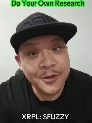 A man is centered in the frame. He is wearing a black baseball cap and a black shirt. Above him in a green box it says, 'Do Your Own Research'. Below the man with white text it says 'XRPL: $FUZZY'. The background is a plain, light gray.