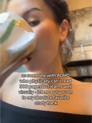 A woman is shown from the chest up, holding a white mug with a green and yellow design near her face. The background is slightly blurred, suggesting an indoor setting, possibly a kitchen, with warm lighting.