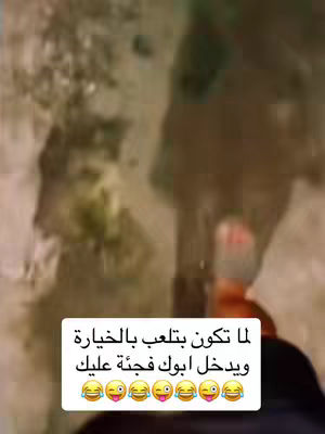 The video shows a blurred background with a text overlay at the bottom. The background appears to be an outdoor setting with hints of trees, and the image is largely brown and green. The text overlay features Arabic script over a white background, with several laughing emojis.
