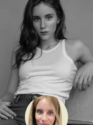 A black and white image featuring a woman in a white tank top and dark jeans, with a superimposed, blurred face of a woman at the bottom. The central figure is looking directly at the camera, with long hair softly framing her face. The blurred face at the bottom of the image is placed within a white circle.