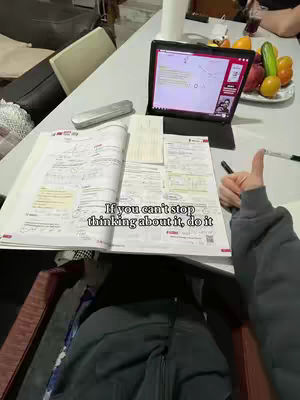 The image shows a person's hand giving a thumbs up, with a partially visible book and laptop on a table. There is motivational text overlaid that says "If you can't stop thinking about it, do it". The background shows parts of a room with a plate of fruit.