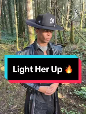 A person in a black hat and jacket stands in a forest setting with a text overlay that says "Light Her Up" with a flame icon.