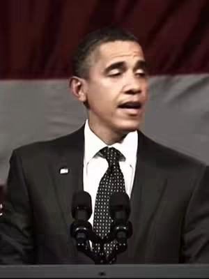 The cover image features a medium shot of Barack Obama speaking into two microphones. He is wearing a dark suit, a white shirt, and a patterned tie. The background appears to be a blurred scene with dark red hues.