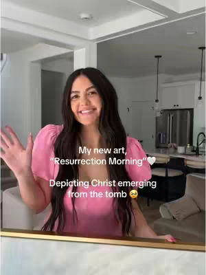 A woman with long dark hair is standing in front of an artwork, smiling and waving. The artwork is in a gold frame. Text overlays the image, describing the artwork as "Resurrection Morning" and stating it depicts Christ emerging from the tomb.