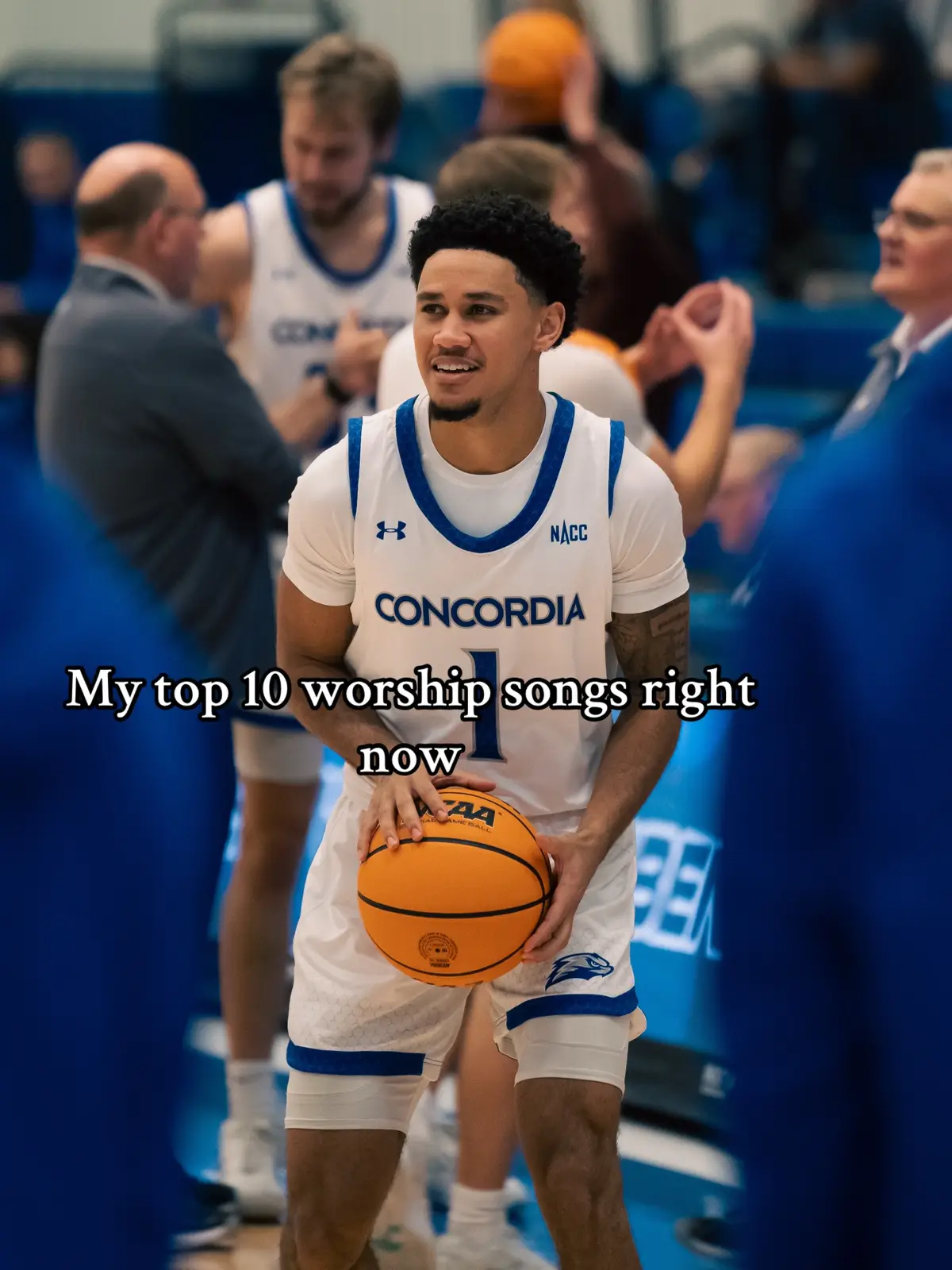 A young Black man in a basketball uniform smiles and holds a basketball on a court, with text over his image.