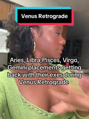 A woman with dark skin and curly hair is shown in a medium shot from the chest up, with her head turned slightly to her right profile. She has gold hoop earrings and is wearing a light green sweater. The background is a room with light wood-colored furniture and a blurred background with two framed pictures. Over her head is a banner that says "Venus Retrograde."