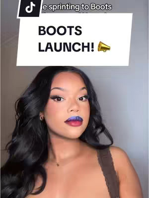 A woman with dark wavy hair and full makeup poses for the camera against a light background. A white rectangle with the text 'BOOTS LAUNCH!' is above her head. She is wearing a brown top. The lip color is transitioning from blue to red. The photo is taken from the chest up.