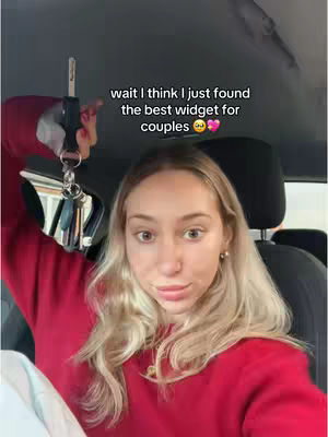 A young woman with long blonde hair is seated inside a car, holding up a car key. She is wearing a red sweater. Text overlayed on the image says, \"wait I think I just found the best widget for couples\"
