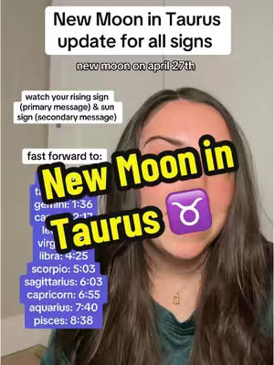 A woman is centered in a selfie-style video with several text overlays. She has long brown hair and is wearing a teal top. The background appears to be a white wall. Overlaid text includes phrases related to astrology and the new moon in Taurus, along with the Taurus zodiac symbol.