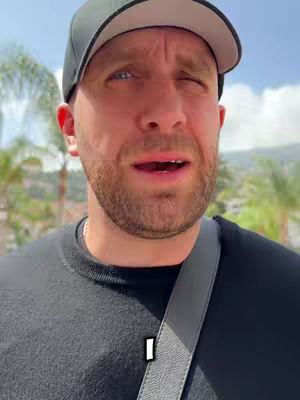 The cover image shows a man in a black cap and shirt, with a blurred background of greenery and a blue sky. The man has a partial expression, the sky is sunny, and a word "I" is added to the image.