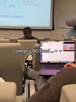 The image shows a classroom setting. A person is sitting in a chair with their legs extended toward a laptop displaying content. On the top-left, there's a projection screen. In the background, there's another individual facing the screen. The hook displays 'college is NOT real'.
