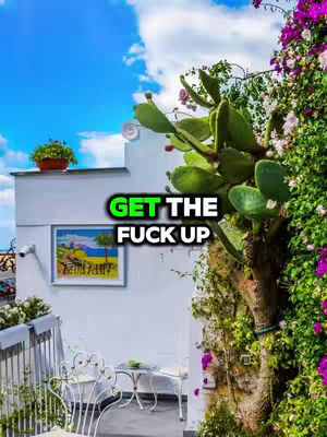 A vibrant image of a bright blue sky filled with wispy clouds. In the foreground, a white wall with a painting, a round table, and a chair. To the right, a lush arrangement of green cacti and flowering plants. The overall composition is sunny and eye-catching.