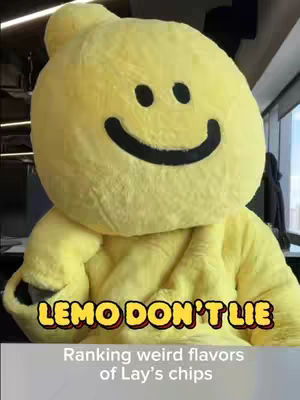 The cover image features a person in a full-body yellow costume shaped like a lemon with a large, smiling face on the head. Below the figure is a text overlay that says "LEMO DON'T LIE" in a stylized font with a yellow outline and a red color fill. Under the text, a grey bar with the text "Ranking weird flavors of lay's chips" is placed, the color palette consists mostly of yellows, black, and a grey.